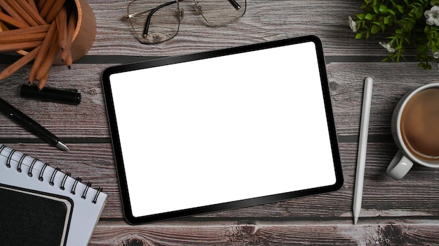 Bovenaanzicht digitale tablet met lege display notebook en benodigdheden op houten bureau