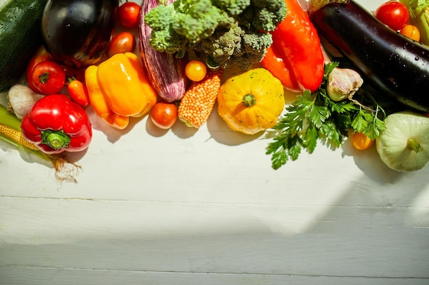 Bovenaanzicht diverse verse biologische groenten op tafel in de keuken in zonlicht kruidenierswinkel gezond winkelen veganistisch foodb plat lag kopieerruimte lay-out met vrije tekst