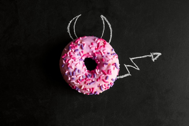 Bovenaanzicht donut op schoolbord met krijt getrokken hoorns en een staart