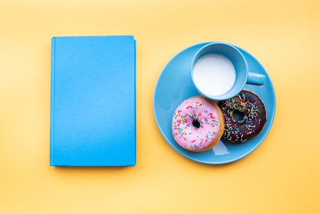 Bovenaanzicht donuts met melk vergezeld van een boek