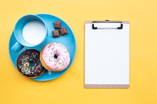 Bovenaanzicht donuts met melk vergezeld van klembord