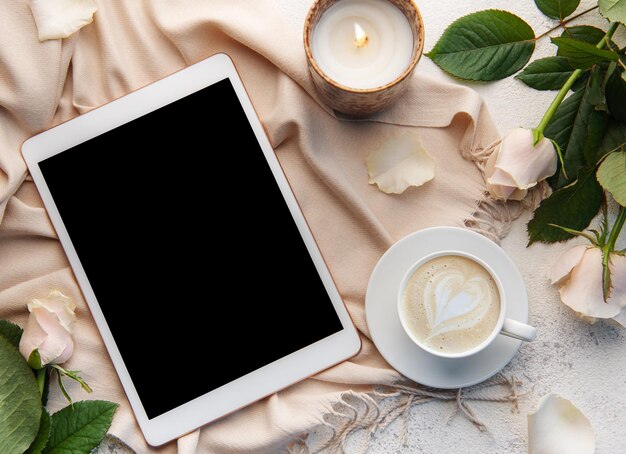 Bovenaanzicht een kopje koffie latte art hartvorm met een roze roos en tablet