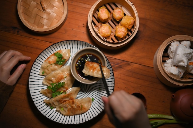 Bovenaanzicht een vrouw die eetstokjes gebruikt die gyoza dompelen in saus aziatisch eten in restaurantconcept