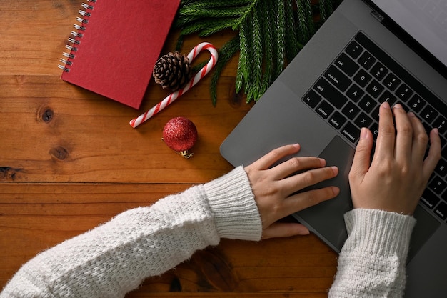 Bovenaanzicht Een vrouw die op het toetsenbord typt met een laptop aan haar bureau met kerstdecor
