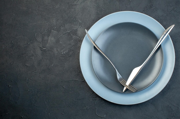 Bovenaanzicht elegante borden met mes en vork op donkere achtergrond genade honger zilverwerk vrouwelijkheid kleurrijke diner