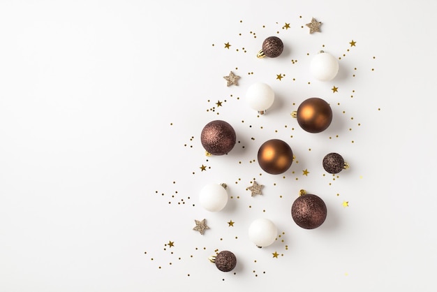 Bovenaanzicht foto van bruin witte en gouden kerstboom decoraties ballen glanzende sterren en pailletten op geïsoleerde witte achtergrond met copyspace