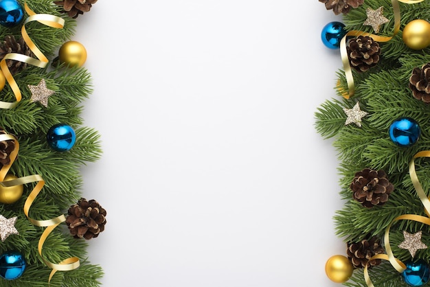 Bovenaanzicht foto van gouden en blauwe kerstboom ballen dennenappels kleine sterren en serpentine op pijnboomtakken op geïsoleerde witte achtergrond met lege ruimte