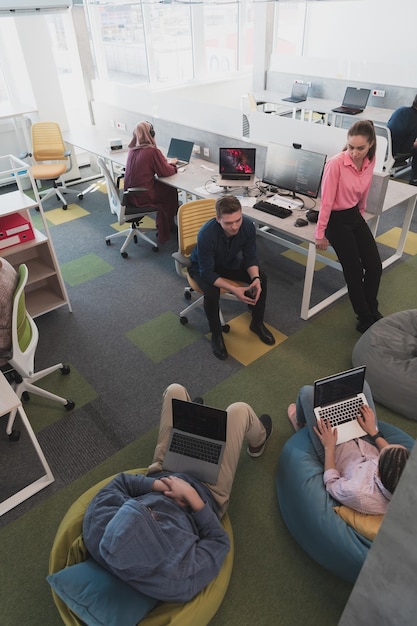 Bovenaanzicht foto van het samenwerkingsproces van het multiculturele bekwame jonge zakelijke team tijdens brainstormbijeenkomst op kantoor. Een diverse groep jonge mensen gekleed in formele kleding die samenwerken o