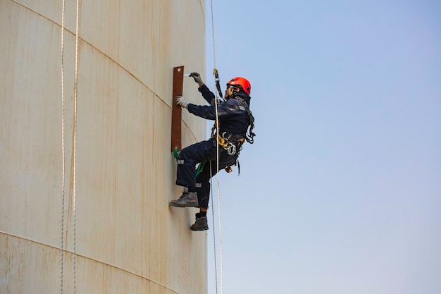 Bovenaanzicht foto van industriële lasser met touwtoegang die op hoogte werkt met harnashelm veiligheidsuitrusting touwtoegangsinspectie van dikte opslagtankindustrie