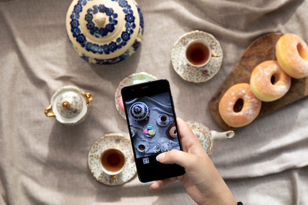 Bovenaanzicht foto van ladyblogger die in café zit en foto maakt met mobiel van food afternoon tea