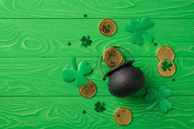 Bovenaanzicht foto van st patrick's day decoraties groene klavers klavervormige confetti en pot met gouden munten op geïsoleerde getextureerde groene houten tafel achtergrond