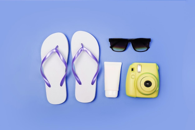 Foto bovenaanzicht foto van strandaccessoires slippers camera zonnebrandbril op geïsoleerde blauwe achtergrond flatlay
