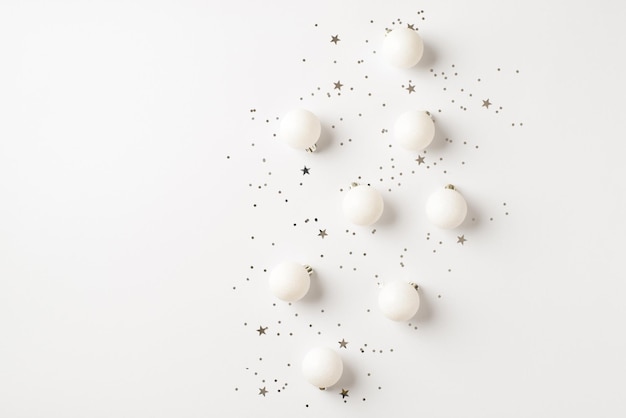 Bovenaanzicht foto van witte kerstboom decoraties ballen en zilveren confetti op geïsoleerde witte achtergrond met copyspace