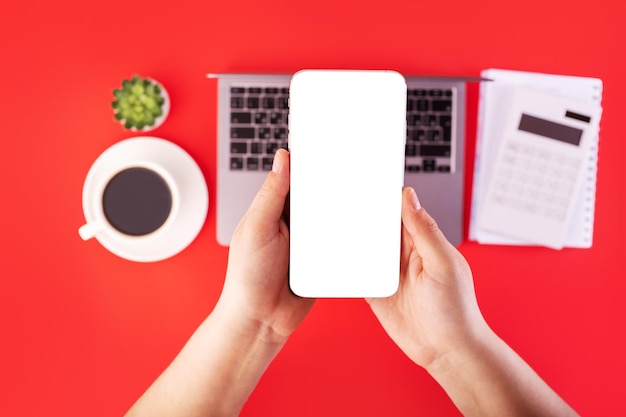 Bovenaanzicht foto van witte rekenmachine en notebook grijze laptop met hand in hand smartphone mockup