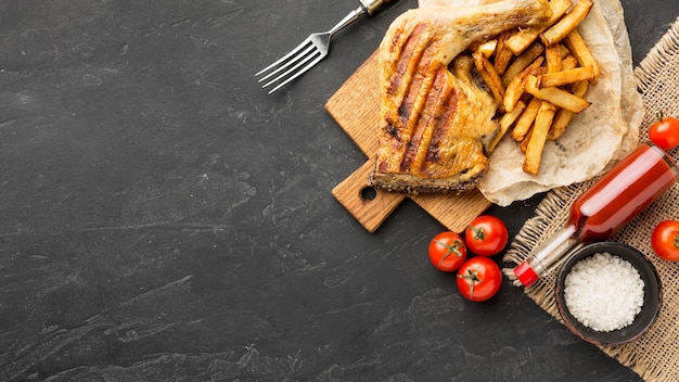 Bovenaanzicht gebakken kip en aardappelen met tomaten en kopie-ruimte