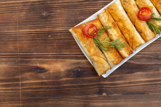 bovenaanzicht gefrituurde greens gebakjes met greens en tomaten in plaat