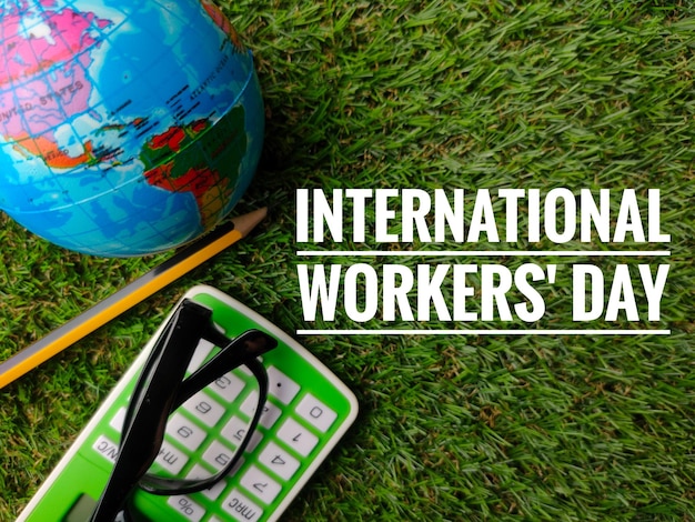 Foto bovenaanzicht globepotlood en rekenmachine met zin international arbeidsdag op grasachtergrond