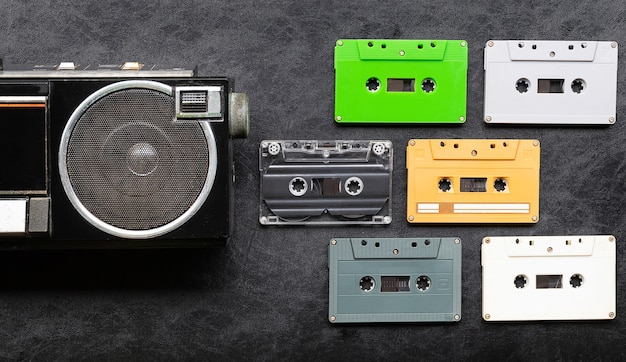 Bovenaanzicht half retro radio en kleurrijke cassetteband op zwarte vloer met kopieerruimte