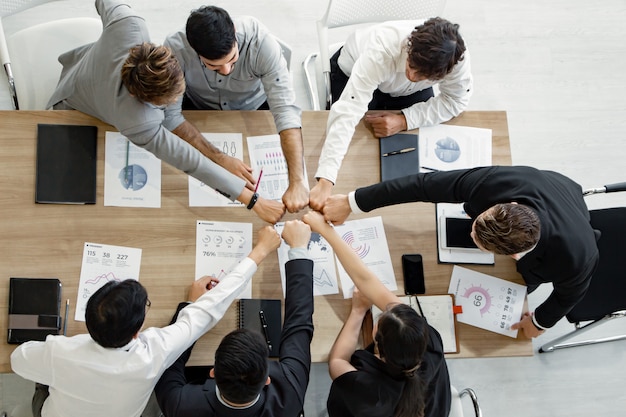 Foto bovenaanzicht hand in hand van team van aziatische mensen en buitenlanders.