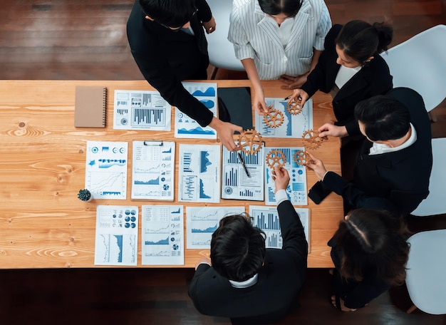 Bovenaanzicht hand met versnelling door groep zakenmensen op tafel in harmonie kantoor