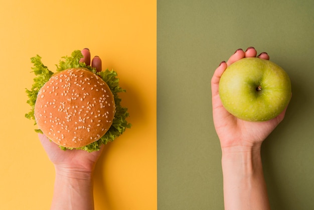 Foto bovenaanzicht handen met hamburger en appel