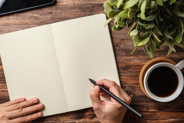 Bovenaanzicht handschrift op notitieboekje en koffiekopje op houten bureau