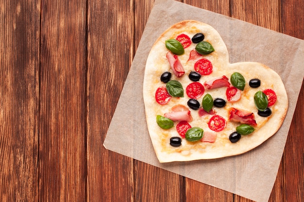 Bovenaanzicht hartvormige pizza op houten tafel