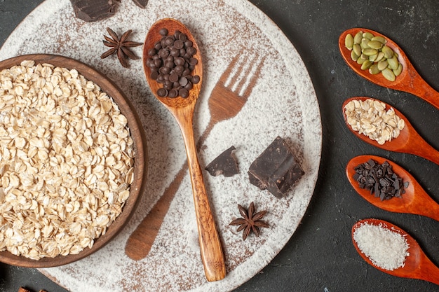 bovenaanzicht havermout in houten kom vork afdruk met poedersuiker donkere chocolade druppels in houten lepel op plaat op tafel