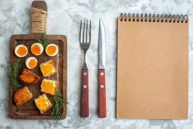 bovenaanzicht heerlijke broodjes met kaviaar en gekookte eieren op snijplank wit oppervlak lunch ontbijt zeevruchten maaltijd visvoer