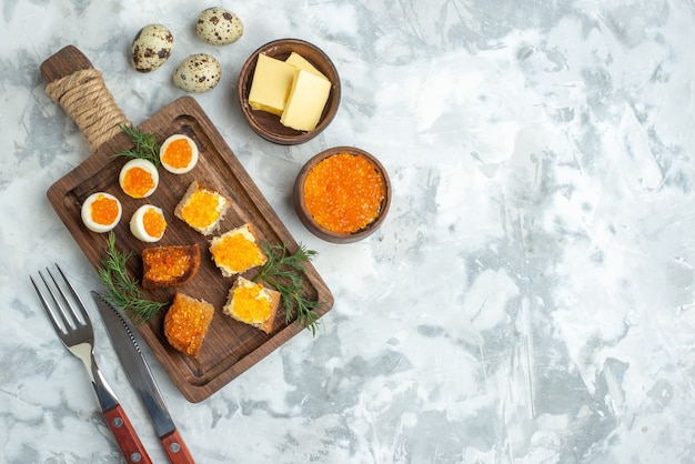 bovenaanzicht heerlijke broodjes met kaviaar en gekookte eieren op snijplank wit oppervlak zeevruchten horizontaal ontbijt vis lunch eten