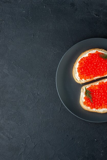 bovenaanzicht heerlijke kaviaar sandwiches in plaat op donkere ondergrond