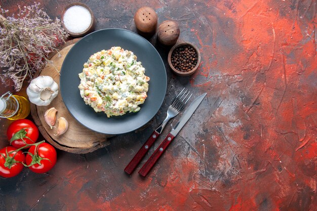 bovenaanzicht heerlijke Russische salade met bestek op donkere ondergrond