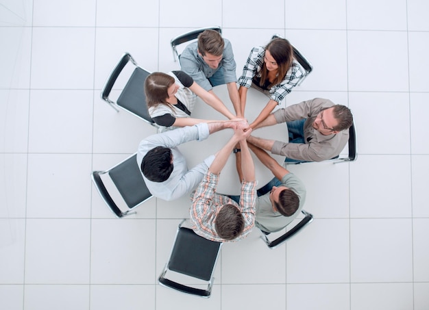 Bovenaanzicht, het lachende zakelijke team vouwde hun handen samen het concept van teamwerk