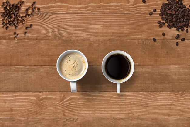 Bovenaanzicht hete zwarte koffie en cappuccino op kopbonen geïsoleerd