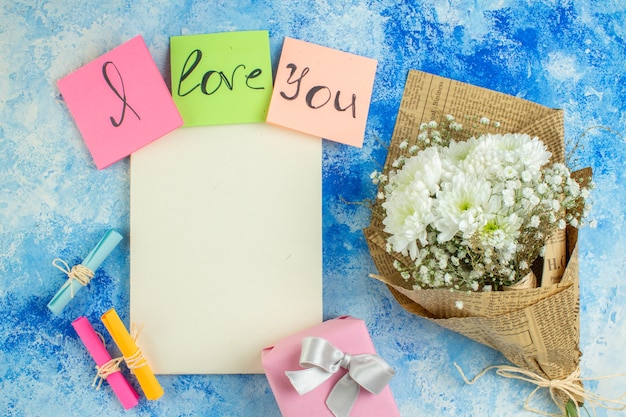 bovenaanzicht ik hou van je geschreven op gekleurde plaknotities scroll wenspapieren witte bloemen notitieboekje op tafel