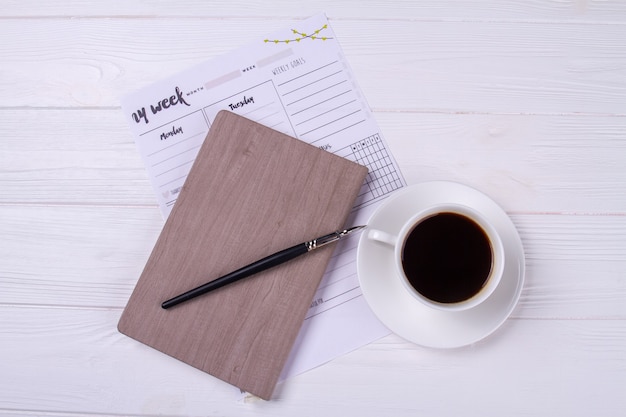 Bovenaanzicht inktpen met dagboek en kopje koffie.