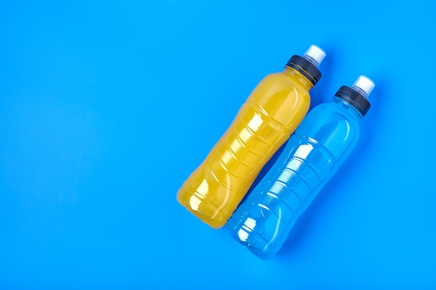 Bovenaanzicht isotone energie oranje gele en blauwe sportdrank in plastic flessen op gele achtergrond