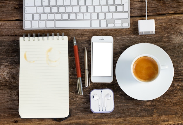 Bovenaanzicht kantoorwerkplek. toetsenbord met telefoon, koffie en notitieboekje op houten tafel