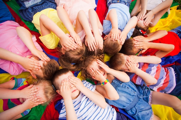 Foto bovenaanzicht kinderen die gezichten bedekken met handen die op een vloer liggen en hun hoofd en haar heel dicht aanraken kinderen proberen te ontspannen na actieve spelletjes