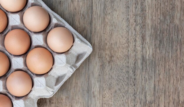 Bovenaanzicht kippeneieren in papieren eierrekje op houten tafel