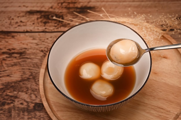 Bovenaanzicht kleefrijst ballen met zwarte sesam in zoete gembersoep op houten tafel.