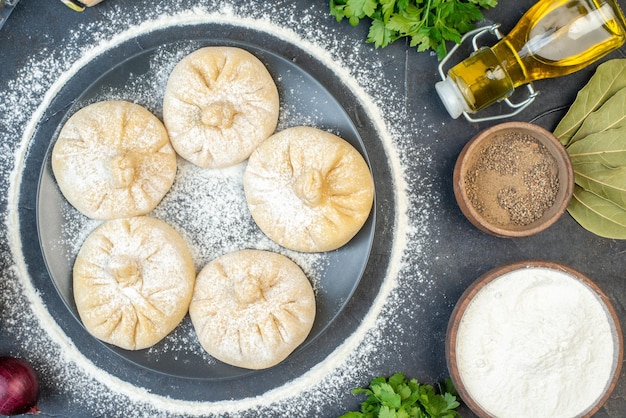 Bovenaanzicht kleine rauwe dumplings met verschillende ingrediënten op de grijze achtergrond voedsel taart taart koken smakelijk vlees deeg kleur meel bakken