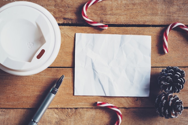 Foto bovenaanzicht koffiekopje en pen, blanco papier op hout met kerstdecoratie voor nieuwjaar concept.
