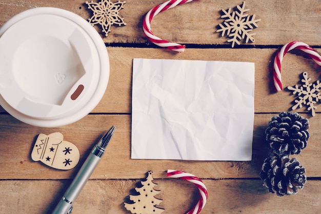 Bovenaanzicht koffiekopje en pen, blanco papier op hout met Kerstdecoratie