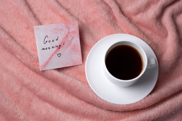 Bovenaanzicht koffiekopje op een roze deken