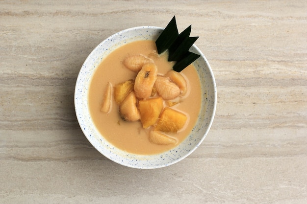 Bovenaanzicht Kolak Pisang Ubi of Banaan en Zoete Aardappel Compote is een populair Indonesisch Dessert gemaakt van Banaan Zoete Aardappel gekookt met Kokosmelk, Palmsuiker en Pandan Bladeren. Populair tijdens Ramadan