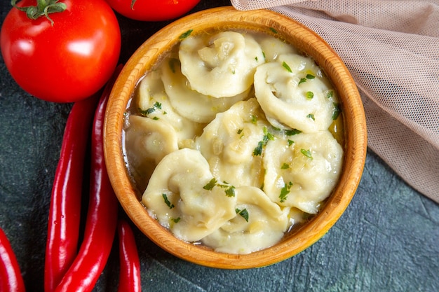 Bovenaanzicht lekker vlees knoedels in houten plaat met verse tomaten op donkere ondergrond