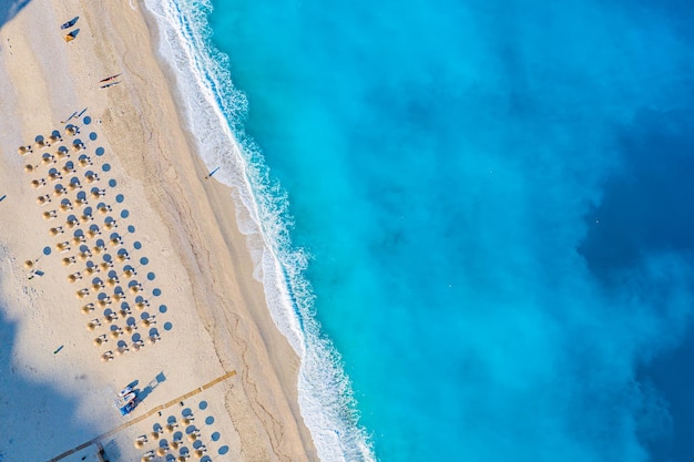 Bovenaanzicht luchtfoto drone foto van Myrtos strand met prachtige turquoise water zee golven en stro parasols vakantie reizen achtergrond Ionische zee Kefalonia eiland Griekenland