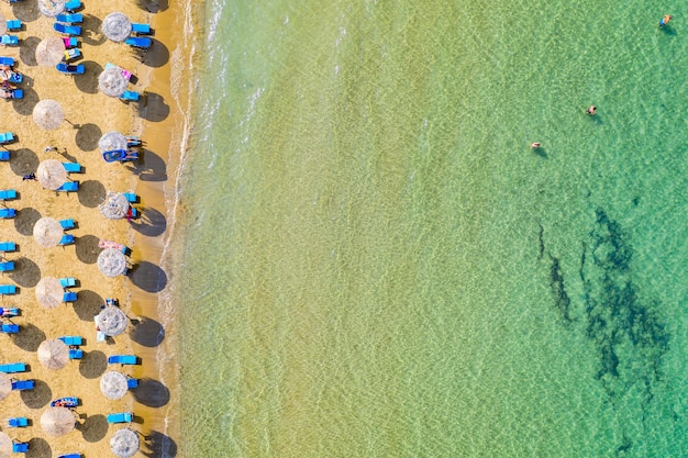 Foto bovenaanzicht luchtfoto drone foto van strand met prachtige turquoise water zee golven en stro parasols vakantie reizen achtergrond ionische zee corfu eiland griekenland