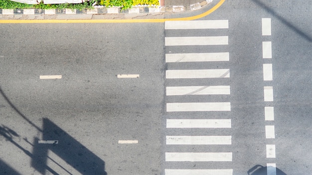 Bovenaanzicht luchtfoto van asfalt spoor en voetgangers zebrapad in verkeersweg met licht en schaduw silhouet